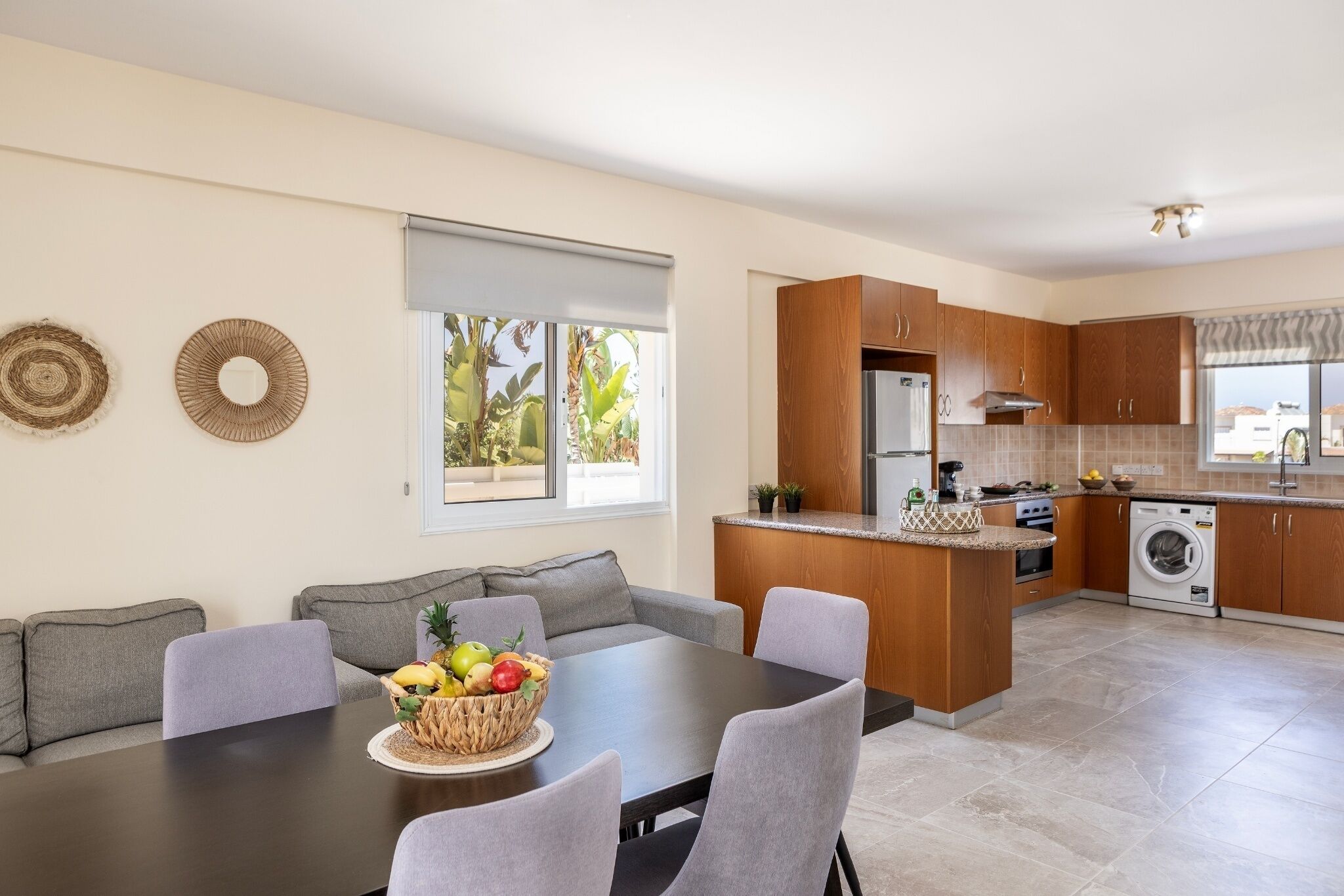 Een moderne keuken met houten kastjes, een eethoek met een tafel en stoelen, en een geïntegreerde wasmachine en droger.