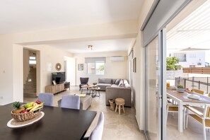 A modern living area with a dining table, sofas, and a TV. - 3 Bedroom Villa In Ayia Triada (Paralimni)