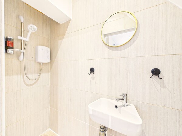 A bathroom with a shower, a sink, a mirror, and a towel rack.