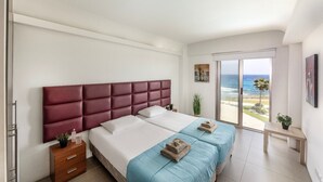 Ein Schlafzimmer mit einem großen Bett, einem Nachttisch aus Holz, einem kleinen Tisch und Blick auf den Strand.