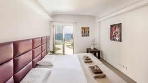 A hotel room with a large bed, a view of the ocean, and two paintings on the wall. - 1 bedroom apartment in Protaras (Paralimni)