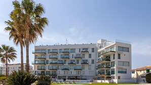 A multi-story hotel with balconies, a swimming pool, and palm trees. - 1 bedroom apartment in Protaras (Paralimni)
