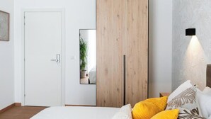 A bedroom with a bed, a wooden wardrobe, a white door, and a wall-mounted light fixture. - Barirooms - Cardassi Suites (Bari)