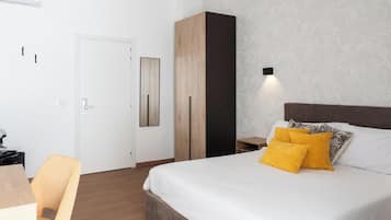 Un dormitorio con cama, armario, escritorio y silla.