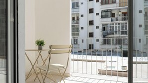 A balcony with a chair, a small table, and a potted plant. - Barirooms - Cardassi Suites (Bari)