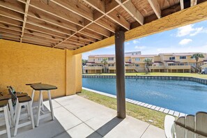 Una veranda coperta con piscina, soffitto in legno e vista su un edificio residenziale.