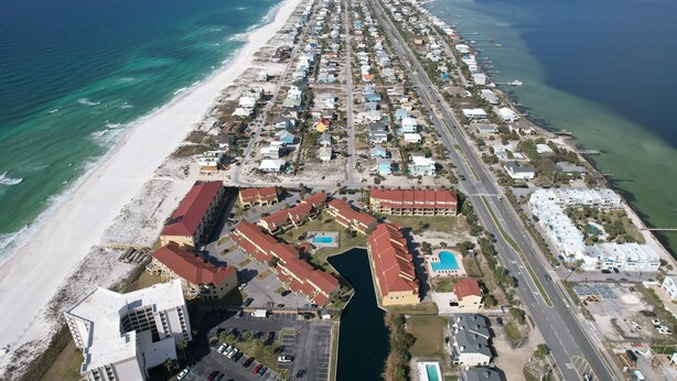 An aerial view of a coastal residential area with a beachfront, a marina, and a road running parallel to the beach. - Spacious 4bedroom 3bathroom townhouse casual elegance w/ lagoon views! 2 Pools! (Pensacola Beach)