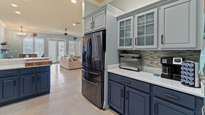 A modern kitchen with a stainless steel refrigerator, dark blue cabinets, and a white countertop. - Spacious 4bedroom 3bathroom townhouse casual elegance w/ lagoon views! 2 Pools! (Pensacola Beach)
