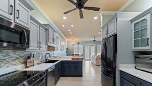 A modern kitchen with stainless steel appliances, a central island, and a ceiling fan. - Spacious 4bedroom 3bathroom townhouse casual elegance w/ lagoon views! 2 Pools! (Pensacola Beach)