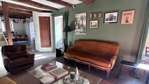 Ein Wohnzimmer mit einem braunen Sofa, einem braunen Sessel, einem Glastisch und einem Kamin.