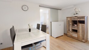 Un comedor con una mesa blanca, sillas, un reloj y un armario de madera.