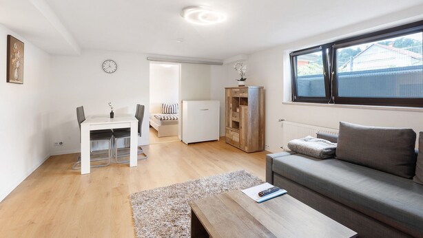 Una sala moderna con un sofá, una mesa de comedor y una zona de cocina.