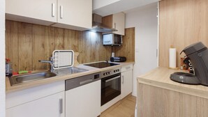 Una cocina compacta equipada con microondas, horno, lavavajillas y cafetera.