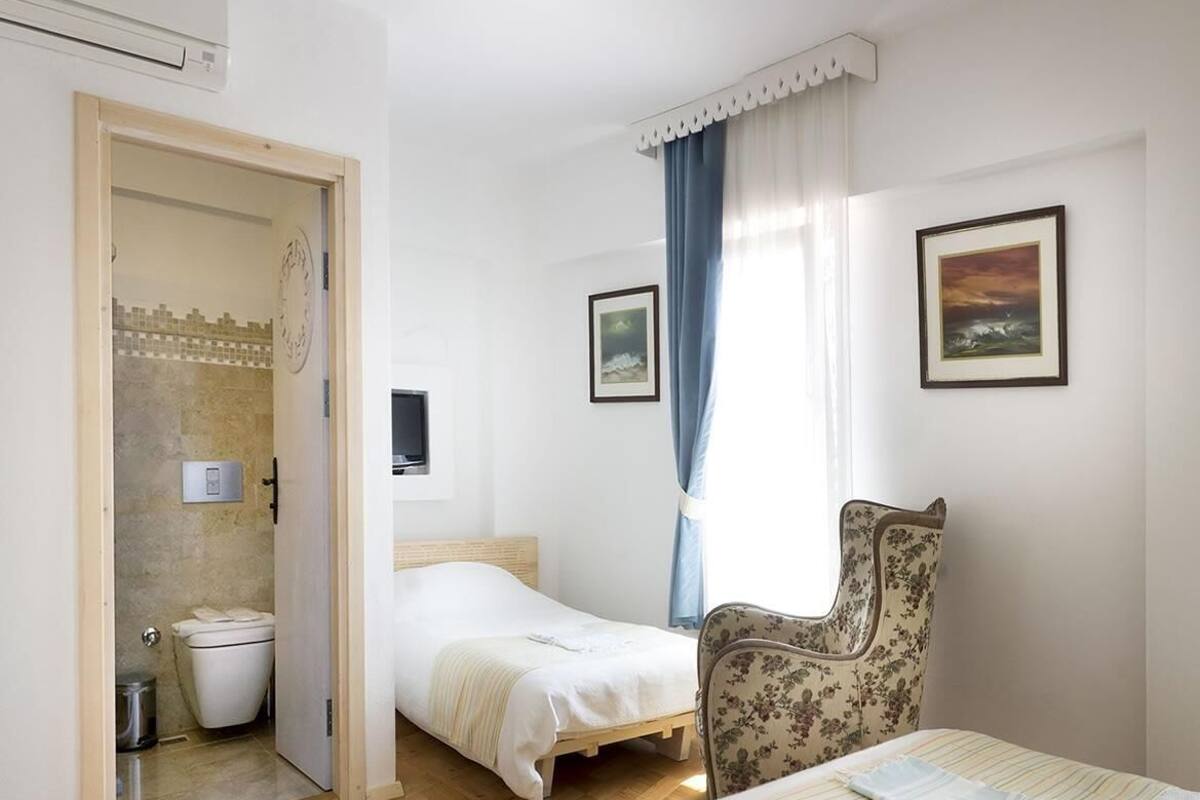 Un dormitorio con dos camas, zona de ducha y una silla.