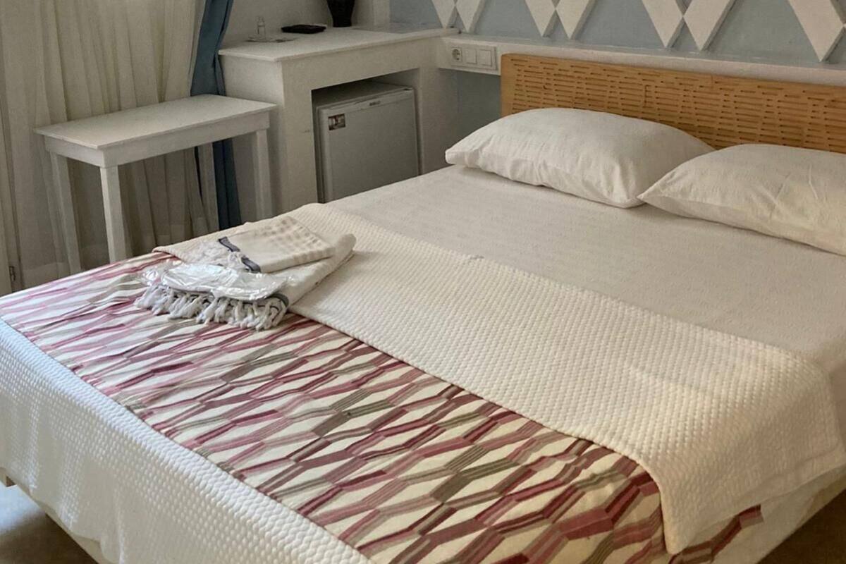 Habitación de hotel con cama, escritorio, refrigerador pequeño, espejo y pared con diseño.