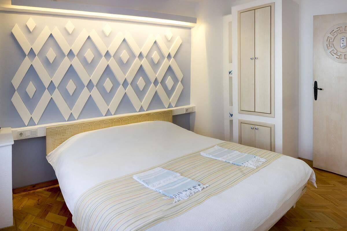 Una cama bien tendida con una colcha a rayas, un aplique de pared y un armario de madera.