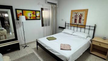 Una camera d'albergo con un letto, un comodino, una lampada, un quadro e uno specchio.