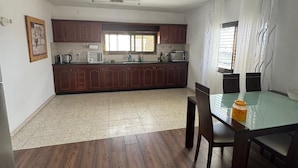 A kitchen with wooden cabinets, a dining table with chairs, and a ceiling light fixture.