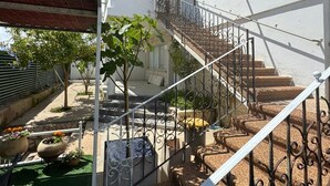 A courtyard with a staircase, potted plants, and a white building.