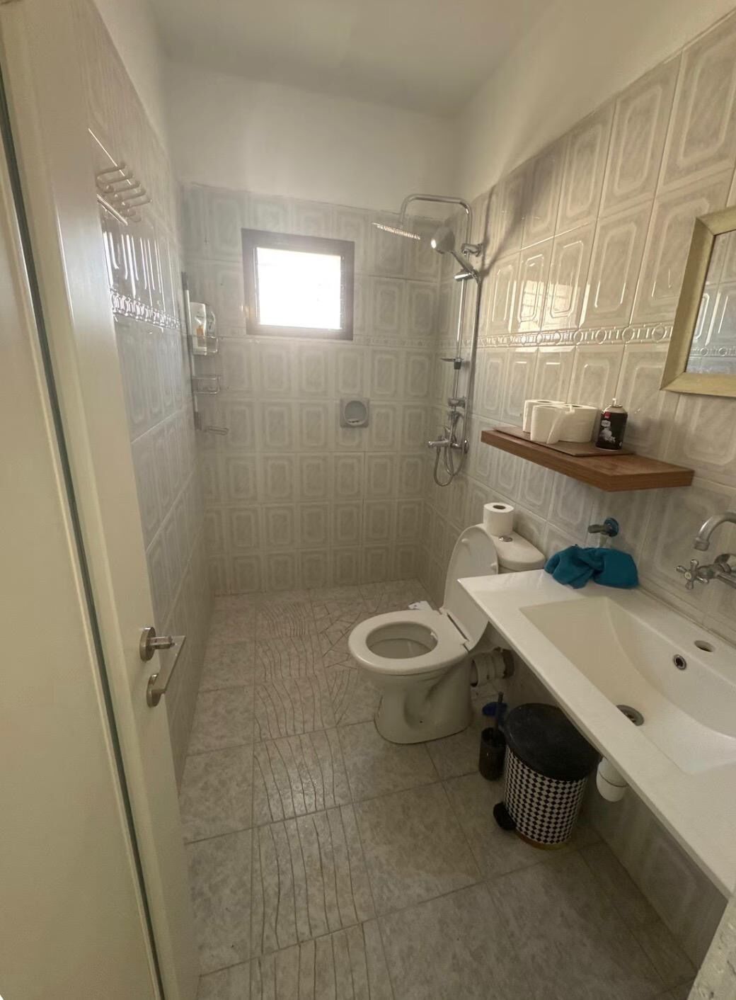 Ein Badezimmer mit Toilette, Dusche, Waschbecken und einem kleinen Fenster.