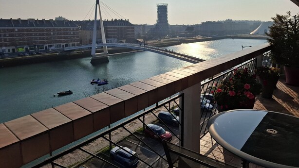 Un balcón con vistas a un río, un puente y edificios al fondo.