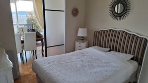 Un dormitorio con cama, mesita de noche, lámpara y un espejo en la pared.