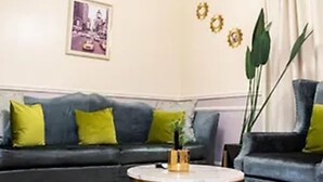 Una sala de estar con un sofá de color oscuro, una mesa redonda y un cuadro enmarcado en la pared.