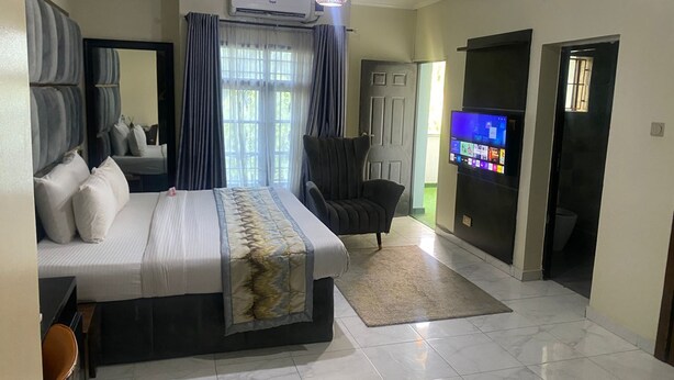 Una habitación de hotel con una cama, una silla, un televisor y un equipo de aire acondicionado.