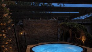 Ett bubbelbad omgivet av en träaltan, en stenmur och en träpergola.