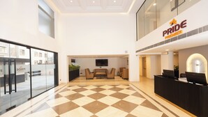 Un hall d’hôtel avec un sol à carreaux, un comptoir d’accueil et un espace salon.