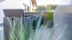 A balcony with wicker furniture, a potted plant, and a metal railing. - Apartment 'Waldquartier Huxel' with Wi-Fi and Air Conditioning (Schmallenberg)