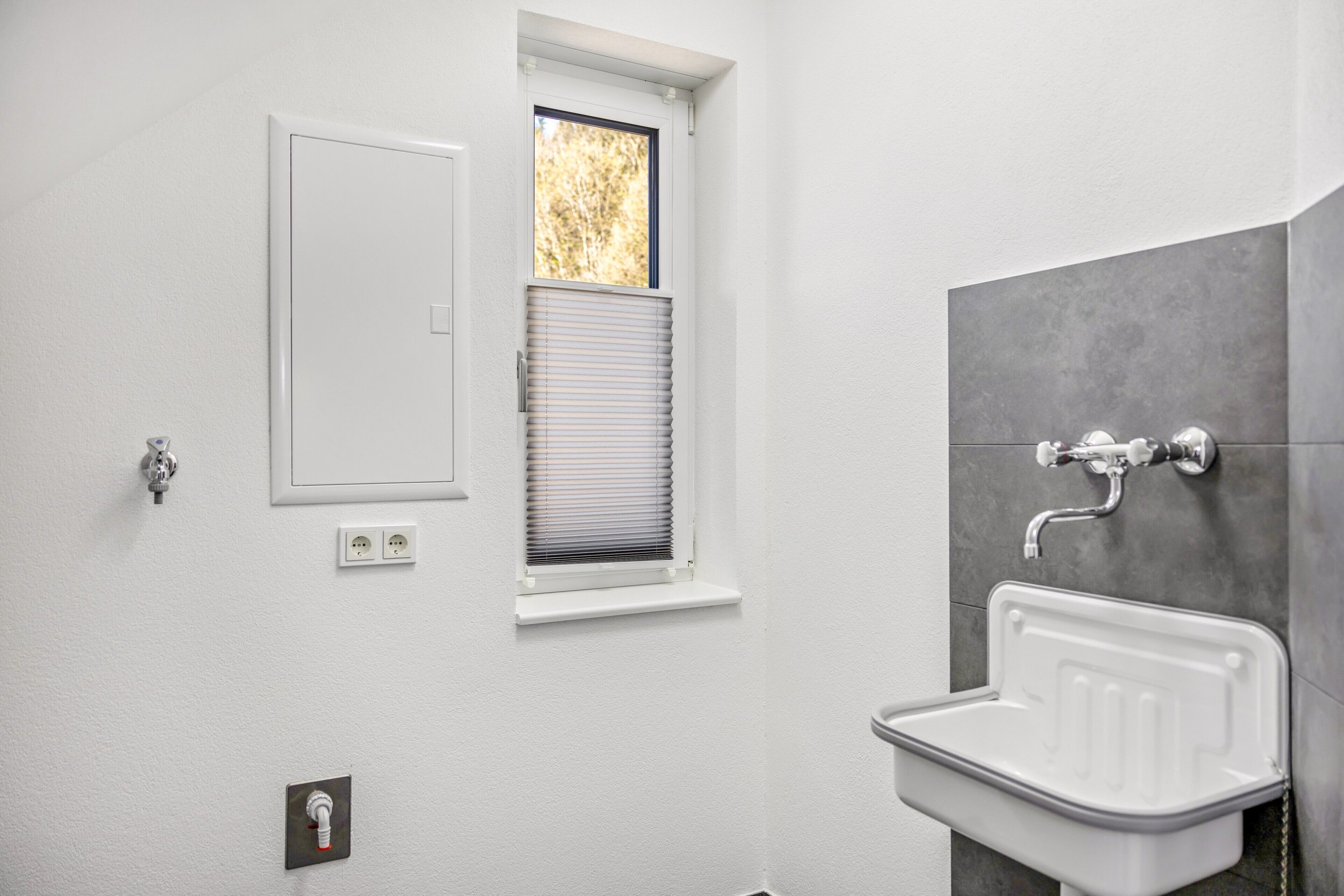 A bathroom with a window, a sink, and a door.