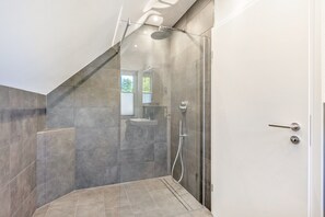 Ein modernes Badezimmer mit einer Duschkabine aus Glas, einem freistehenden Waschbecken und einer Tür mit Griff.