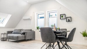 A modern loft with a dining area, grey sofa, and a skylight. - Apartment 'Waldquartier Huxel' with Wi-Fi and Air Conditioning (Schmallenberg)