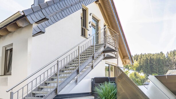 A building with a staircase, a balcony, and a view of trees. - Apartment 'Waldquartier Huxel' with Wi-Fi and Air Conditioning (Schmallenberg)