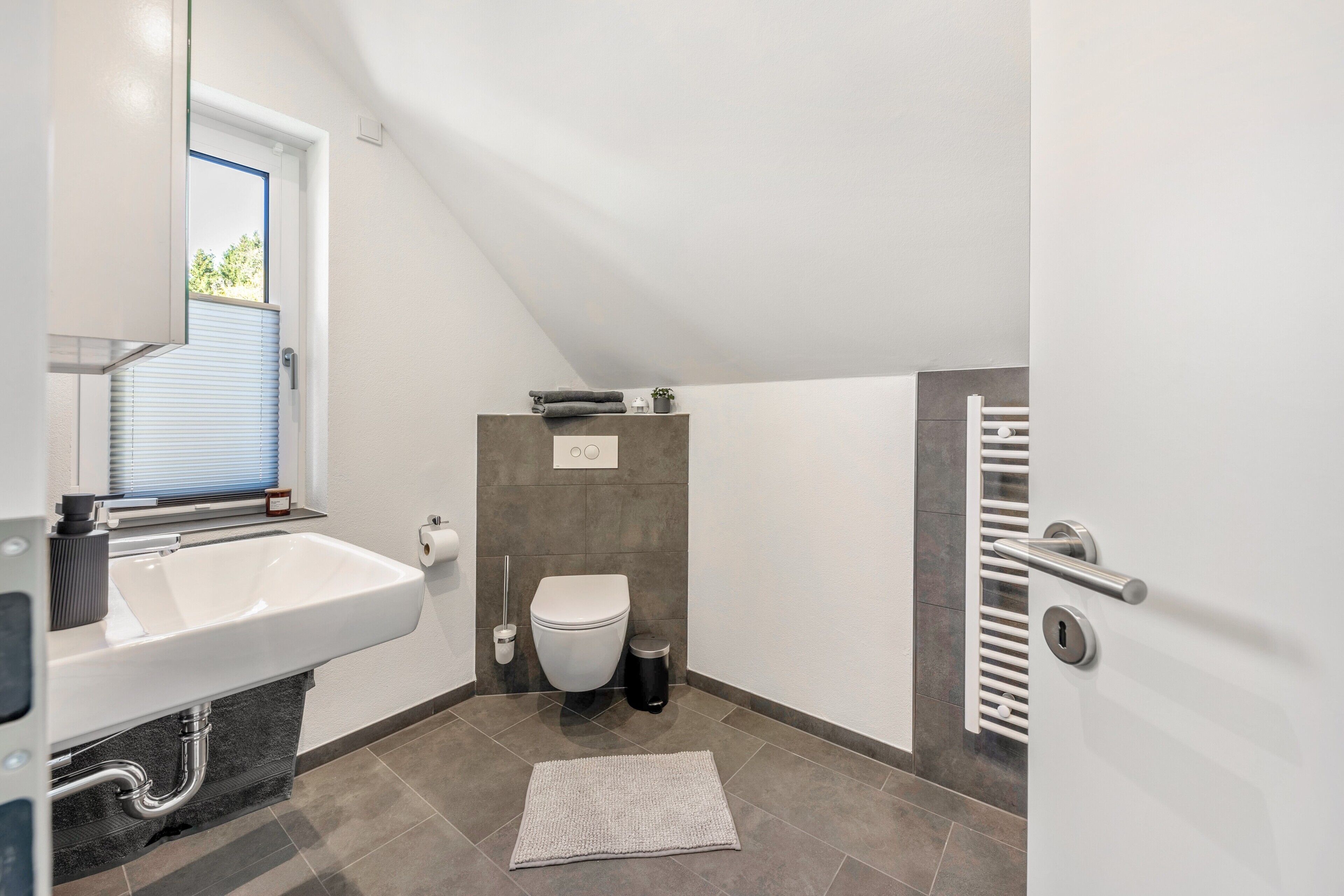Un bagno moderno con lavandino, water e portasciuga in bianco.
