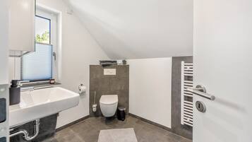 Un bagno moderno con lavandino, water e portasciuga in bianco.