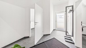 A modern hotel corridor with a door leading to a bathroom, a visible sign, and a plant. - Apartment 'Waldquartier Huxel' with Wi-Fi and Air Conditioning (Schmallenberg)
