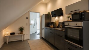 A modern kitchen with a built-in microwave, oven, and a flat-screen TV mounted above the counter. - Apartment 'Waldquartier Huxel' with Wi-Fi and Air Conditioning (Schmallenberg)