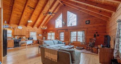 Peaceful log cabin retreat with wraparound deck, open living space, full kitchen, cozy bedrooms & scenic wooded views.