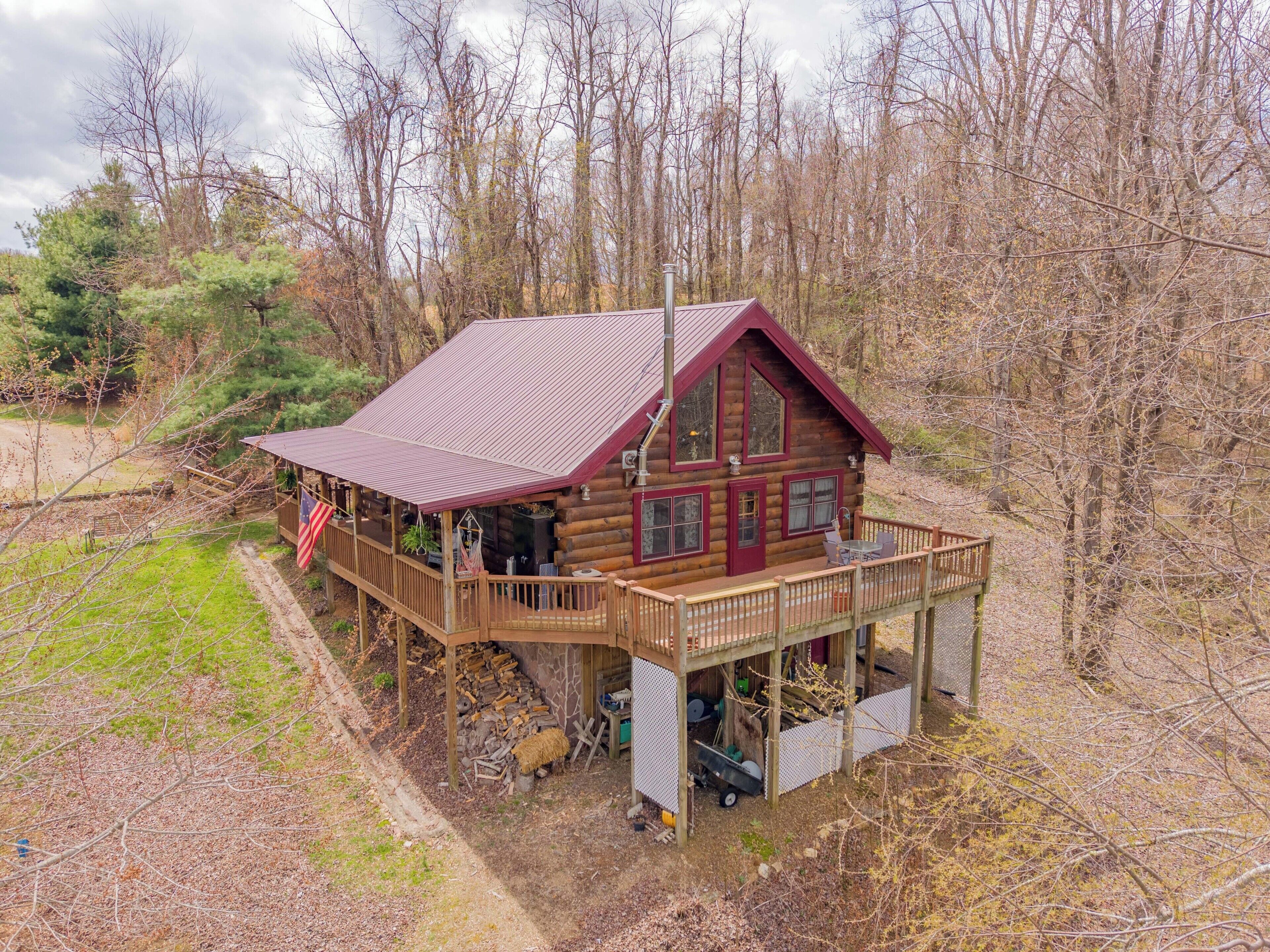 Charming log cabin with a spacious wraparound deck in a peaceful wooded setting.