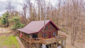 Une cabane en rondins avec un porche, une terrasse couverte et un drapeau.