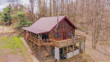 A log cabin with a porch, a covered deck, and a flag.