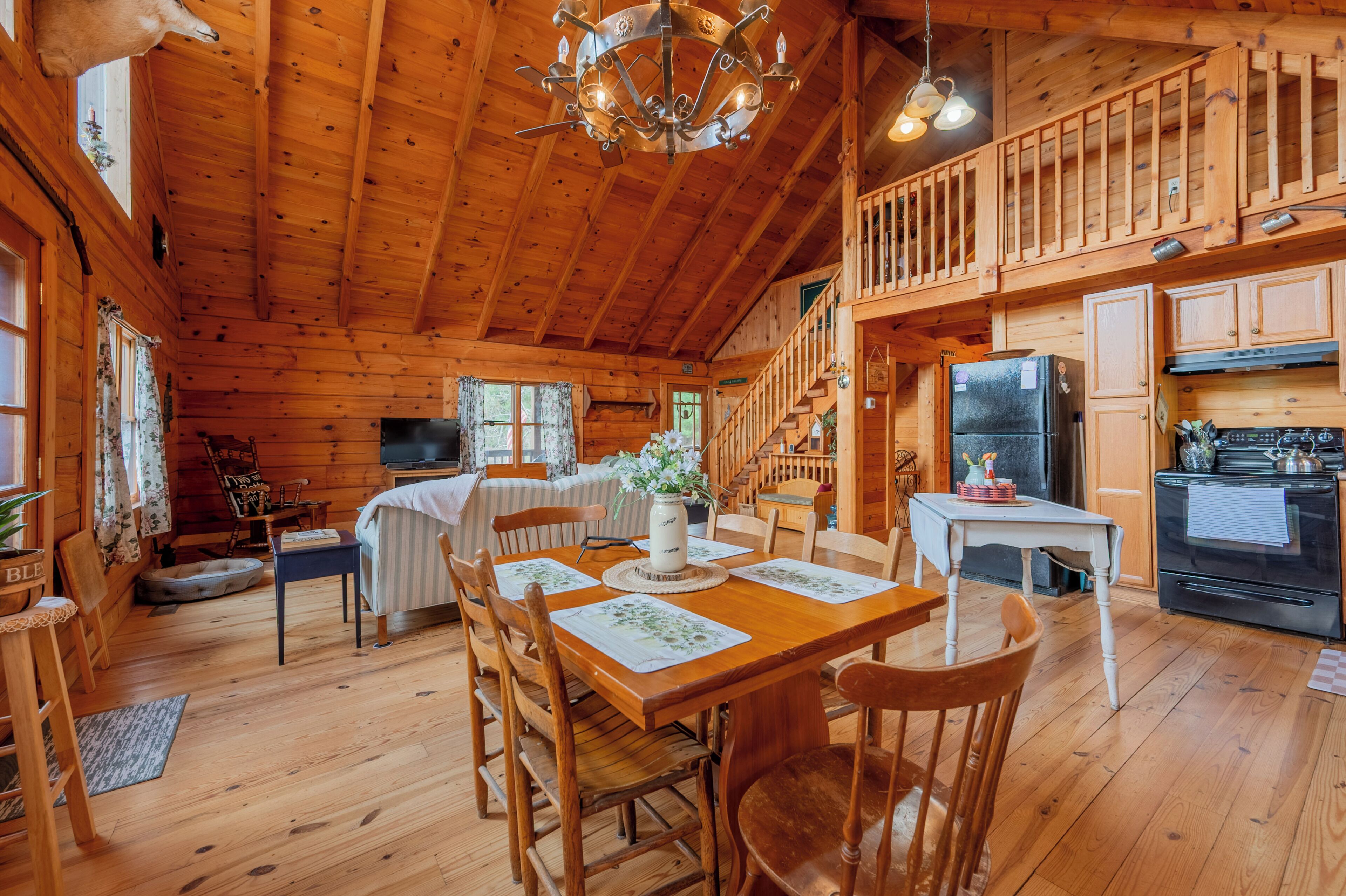 L’intérieur d’une cabane en bois comprend un coin repas, une cuisine et un escalier menant à un niveau supérieur.