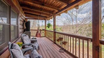 A wooden deck with outdoor seating, a pergola, and a view of the surrounding landscape.