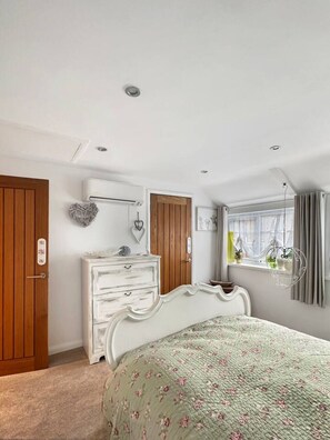 A bedroom with a bed, dresser, and wardrobe. - Cosy 1 bed cottage - Sleeps 4 (Scalford)