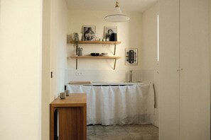 A kitchen with wooden shelves, a white countertop, and a hanging light fixture. - Design Artist Studio Marias - Boulevard Beaumarchais (Paris)