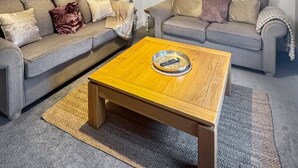 Ein Wohnzimmer mit zwei grauen Sofas, einem Holztisch, einem Bild an der Wand und einer Deckenleuchte.