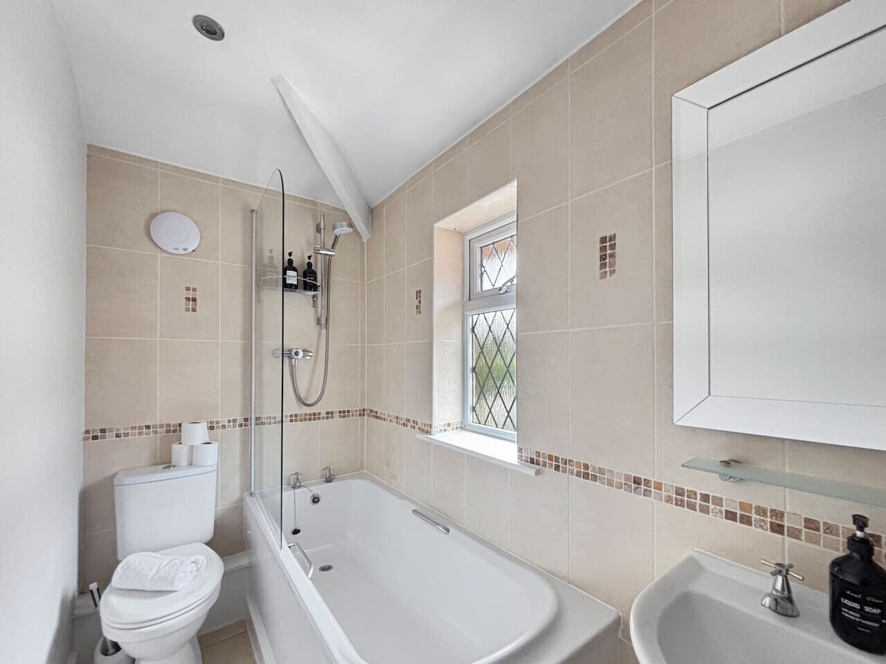 A bathroom with a bathtub, toilet, sink, and a window with a view.