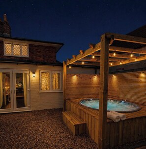 A wooden outdoor hot tub area with a pergola, a brick house in the background, and a gravel ground. - 3 bed cottage sleeps 6 in Harlaxton village (Harlaxton)